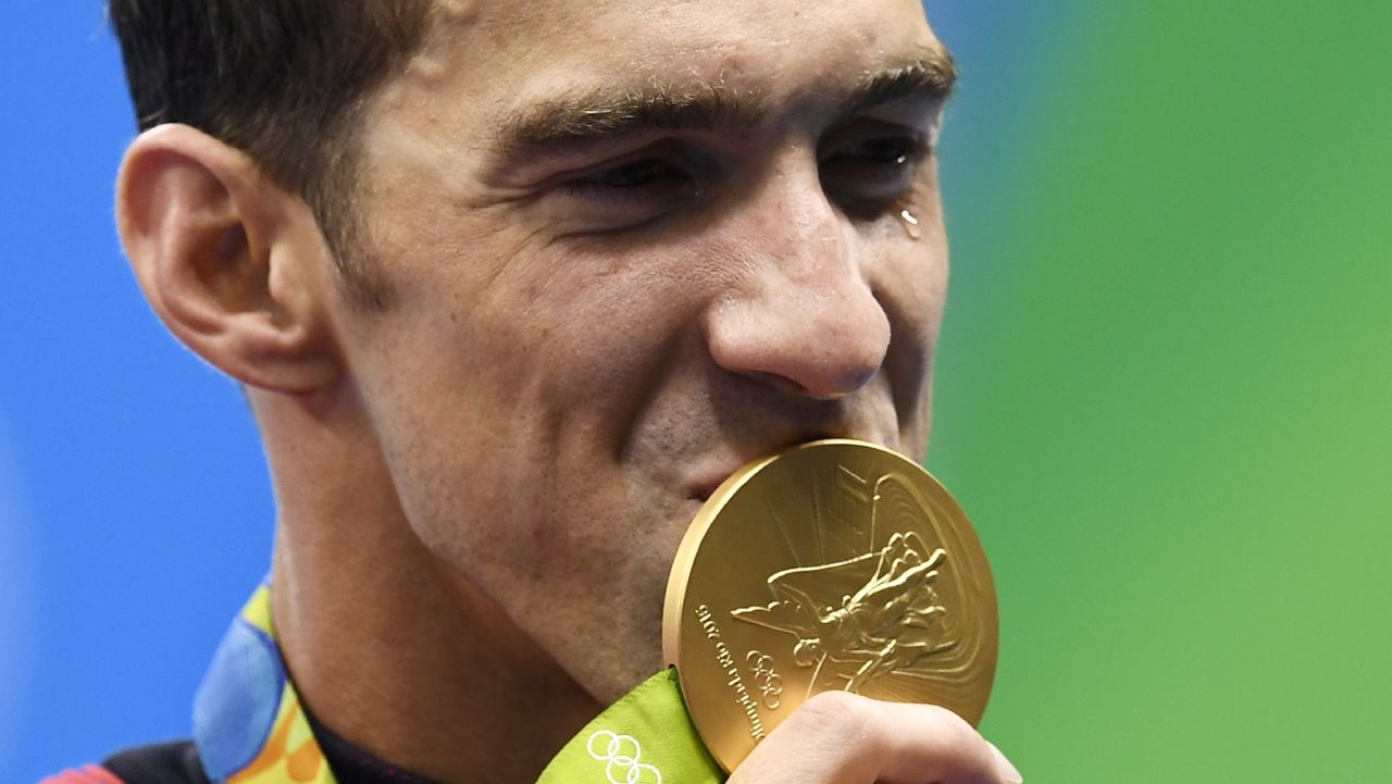 TOPSHOT - USA's Michael Phelps kisses his gold medal on the podium of the Men's 4x100m Freestyle Relay Final during the swimming event at the Rio 2016 Olympic Games at the Olympic Aquatics Stadium in Rio de Janeiro on August 7, 2016.   / AFP / GABRIEL BOUYS        (Photo credit should read GABRIEL BOUYS/AFP/Getty Images)