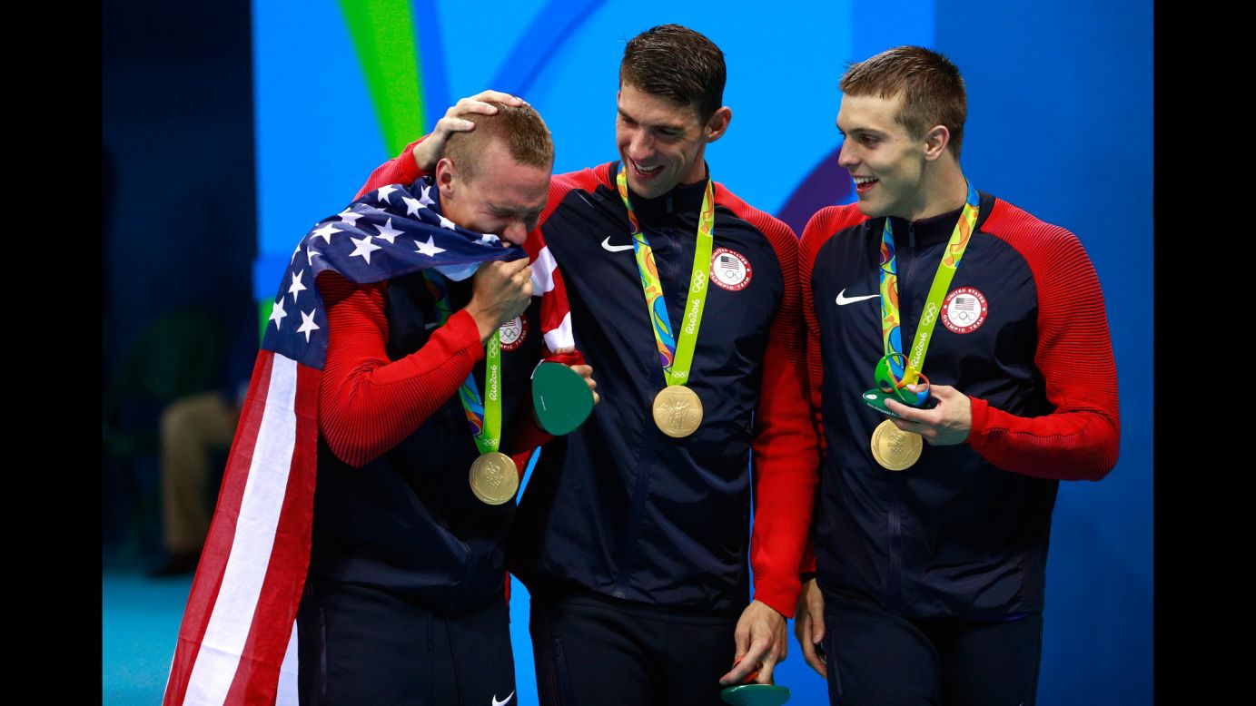 U.S. swimmer Ryan Held cries on the medal stand after winning the 4x100 freestyle relay with Michael Phelps, center, and Caeleb Dressel, right, on Sunday, August 7. Nathan Adrian, not pictured, swam the anchor leg.