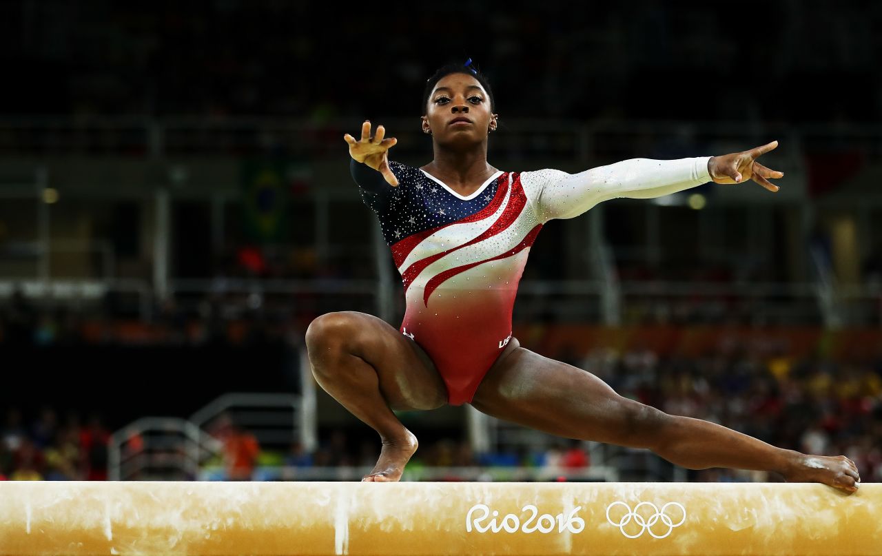 Remember that the balance beam in gymnastics is only 4 inches wide. Near the start of Biles' balance beam performance she does an extremely difficult element called the Wolf Turn. Squatting on her right foot, with her arms and left leg outstretched -- she spins two-and-a-half times around. Then, without falling, Biles stands upright to continue her routine. 
