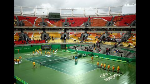 Volunteers dry a rain-soaked court at the Olympic Tennis Center.