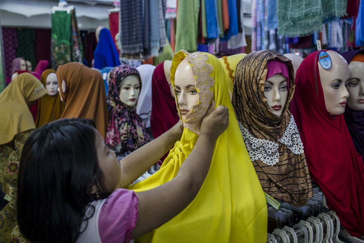 <strong>Hijab:</strong> The scarf worn tightly around the head and neck does not cover the face. It is the most common Islamic head covering. This Indonesian girl is shopping for a hijab in Yogyakarta.