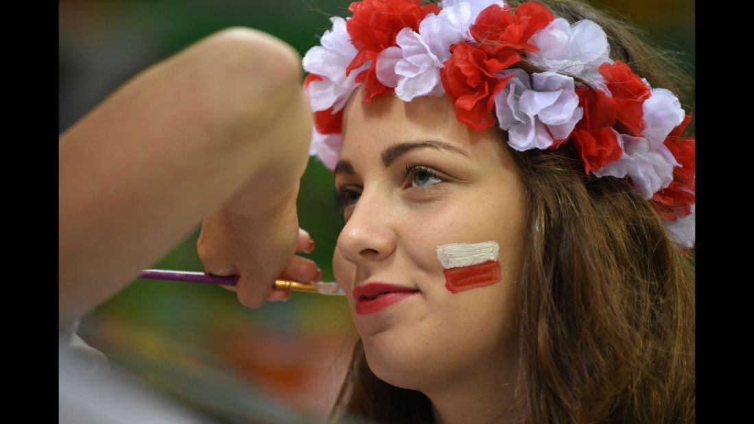 A Poland supporter has her face painted before a handball match.