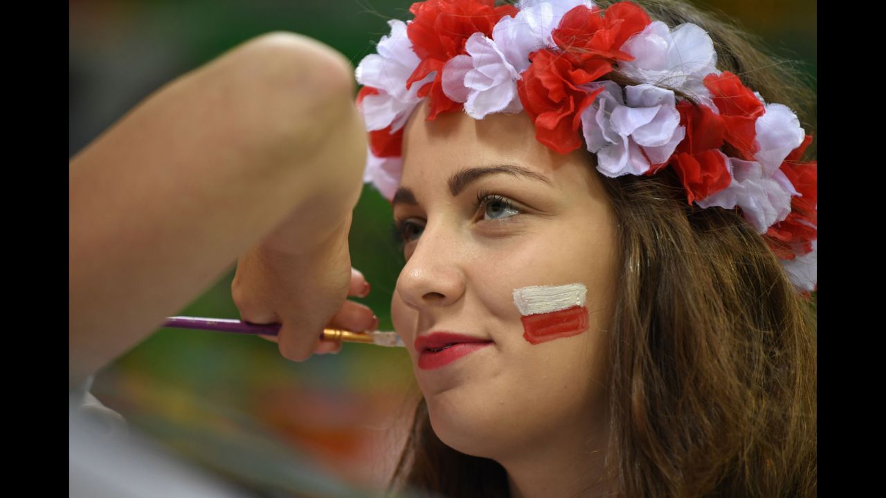 A Poland supporter has her face painted before a handball match.