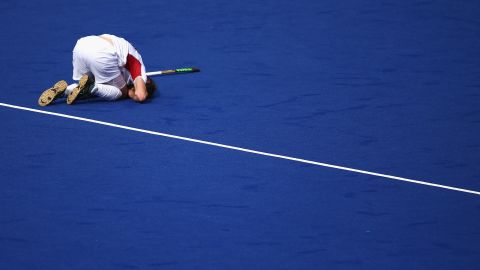 Belgian field hockey player Felix Denayer lies injured on the turf during a match against Spain.
