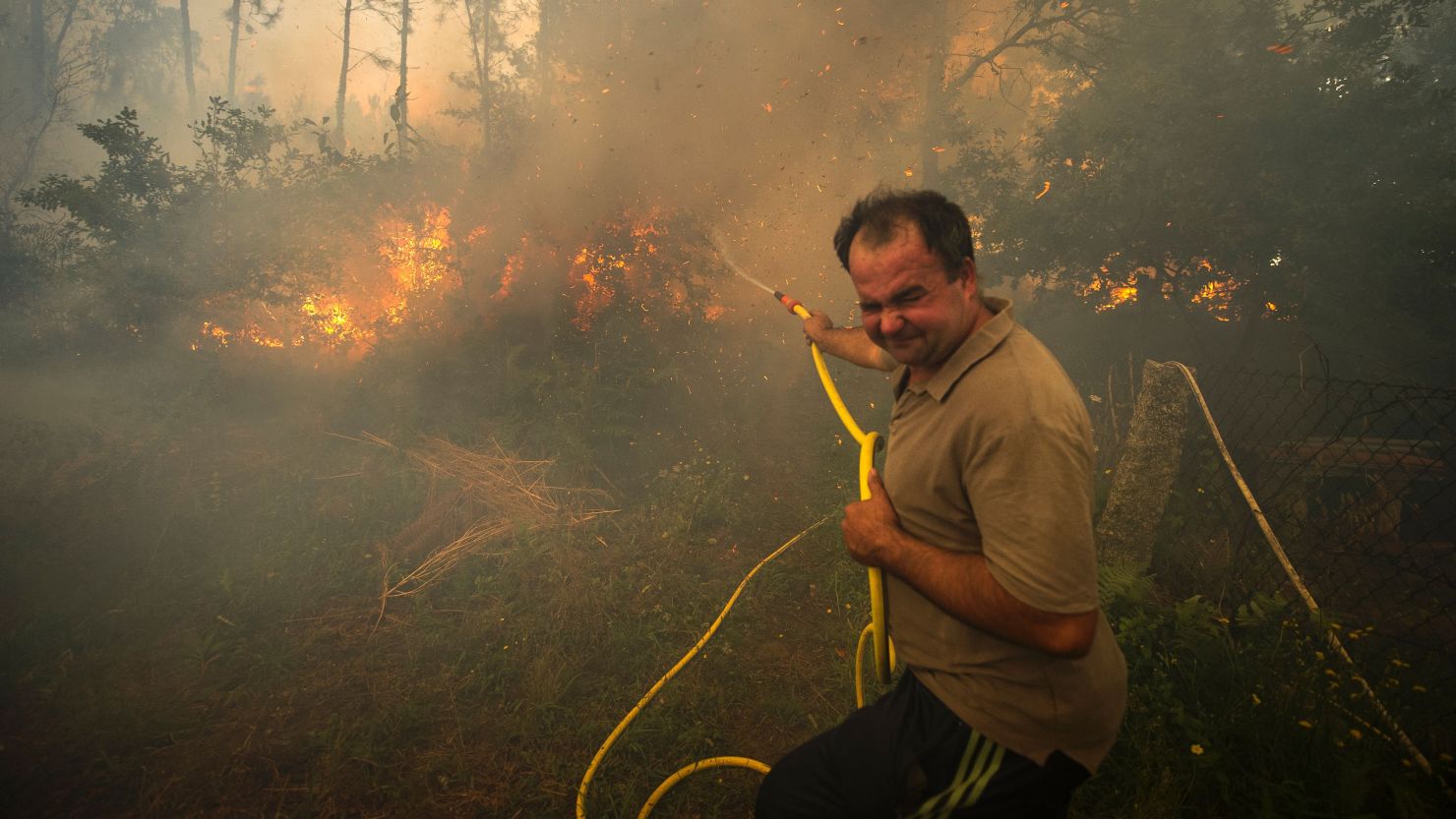 A man fights a wildfire with a garden hose in the Pontevedra region of northwestern Spain Thursday.