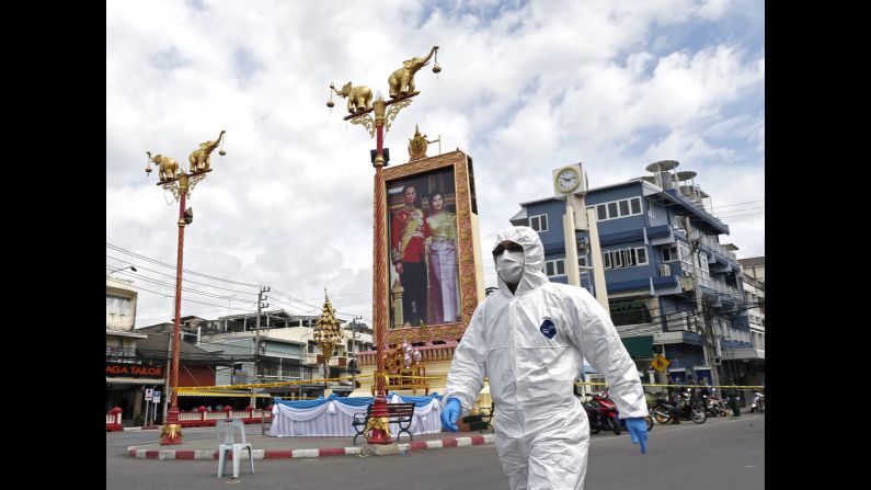 A Thai forensic police officer arrives to investigate the site of a blast after bombs exploded at the clock tower in the center of Hua Hin on August 12. The  attacks were carried out on a public holiday, celebrating Mother's Day and the birthday of Queen Sirikit, pictured here in a large portrait with Thai King Bhumibol Adulyadej.