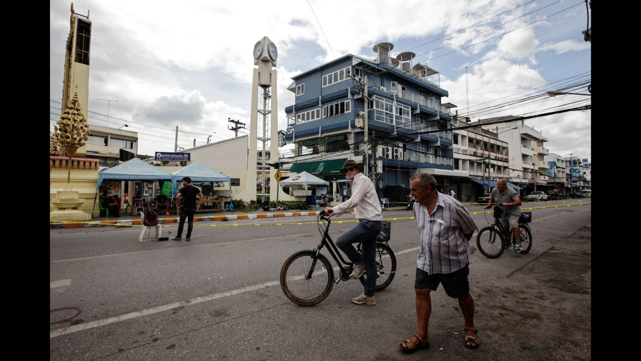 Tourists ride bicycles past the site of an explosion on Friday, August 12 in Hua Hin, Thailand.