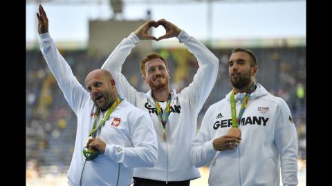Gold medalist Christoph Harting, center, and bronze medalist Daniel Jasinski, right, both of Germany, stand on the podium with silver medalist Piotr Malachowski of Poland to celebrate their discus throw wins.
