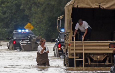 Jeff Robinson lowers a ladder from a National Guard truck as his wife wades through floodwaters near their home in Baptist, Louisiana, on August 13.