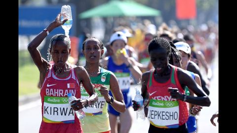 Eunice Jepkirui Kirwa of Bahrain tries to stay cool by pouring water on her head as she runs alongside Visiline Jepkesho of Kenya.