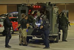 Police officers take an injured man in an armored vehicle to a hospital.