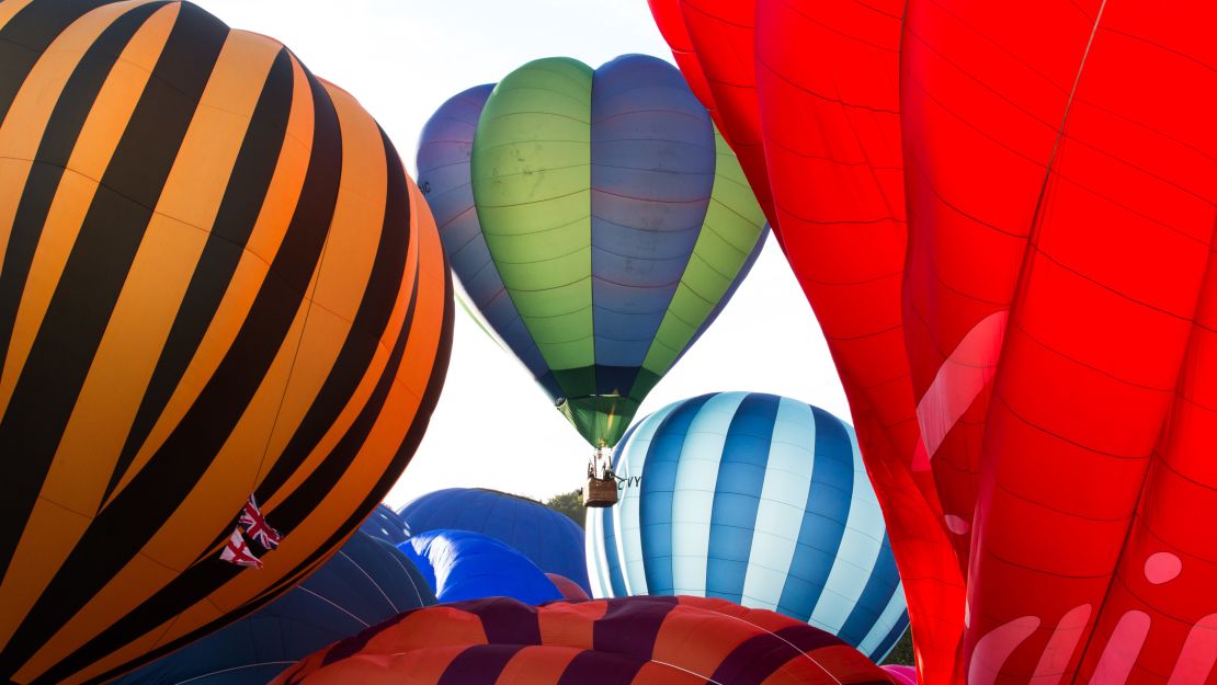 Passengers of a balloon (center), brush against the inflating envelope of another balloon as they lift off en mass on Saturday.