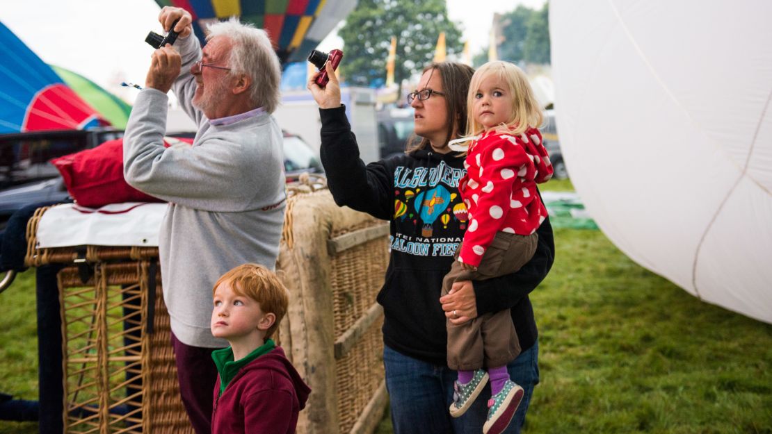 A family watches and waits for the morning lift on Sunday as balloons inflate on the launch field.
