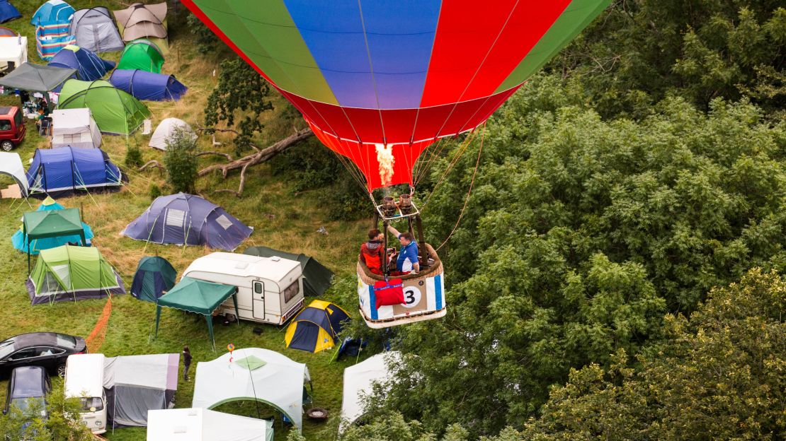 A balloon drifts just above the treeline near a camp site at Ashton Court. 