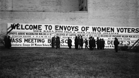 After the march, people mill around a pro-suffrage sign in Washington.