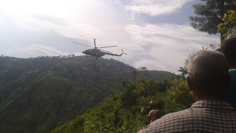 A helicopter lifts off from the mountainous site of a bus crash in Nepal.
