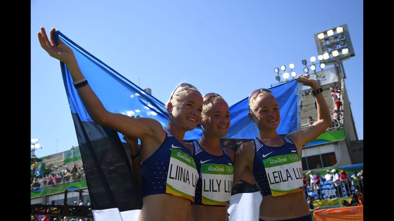 Triplets Liina Luik, Lily Luik and Leila Luik pose with the Estonian flag after taking part in the marathon on Sunday, August 14.