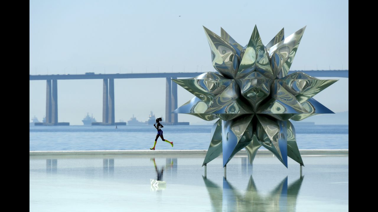A woman runs by the Puffed Star II sculpture during the Olympic marathon on Sunday, August 14.