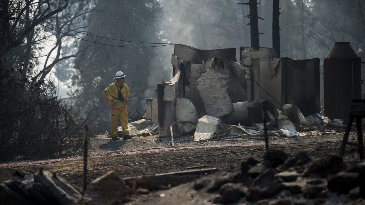 A firefighter from Palo Alto inspects damage from the Clayton fire near Main Street in Lower Lake.