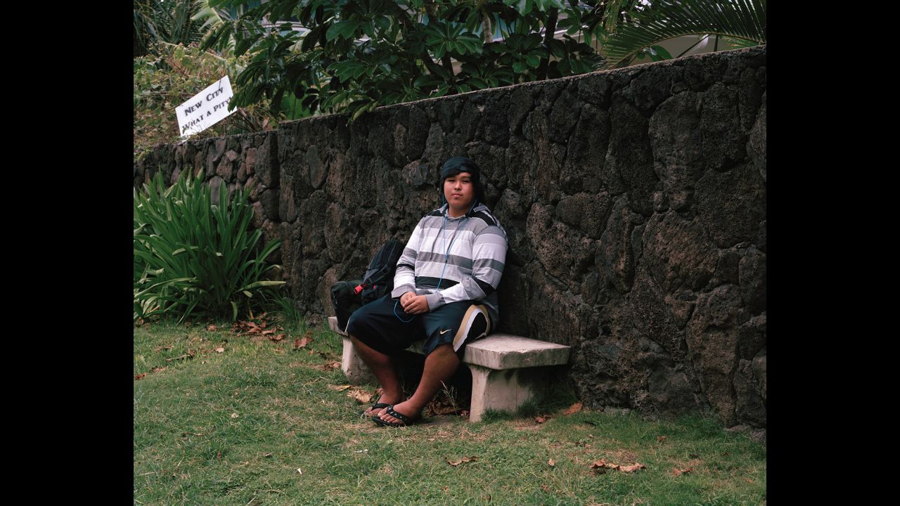 Keoni sits on a bus-stop bench. The sign in the upper left references that the area is up for development, Jung said. "A lot of people want to keep the country the country," Jung said. "They're saying, 'We don't want any more development.' You see that happening a lot here."