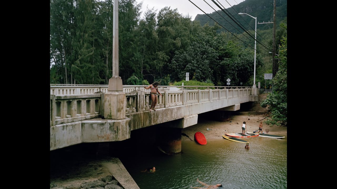 A woman stands on a bridge in Kahana Bay.
