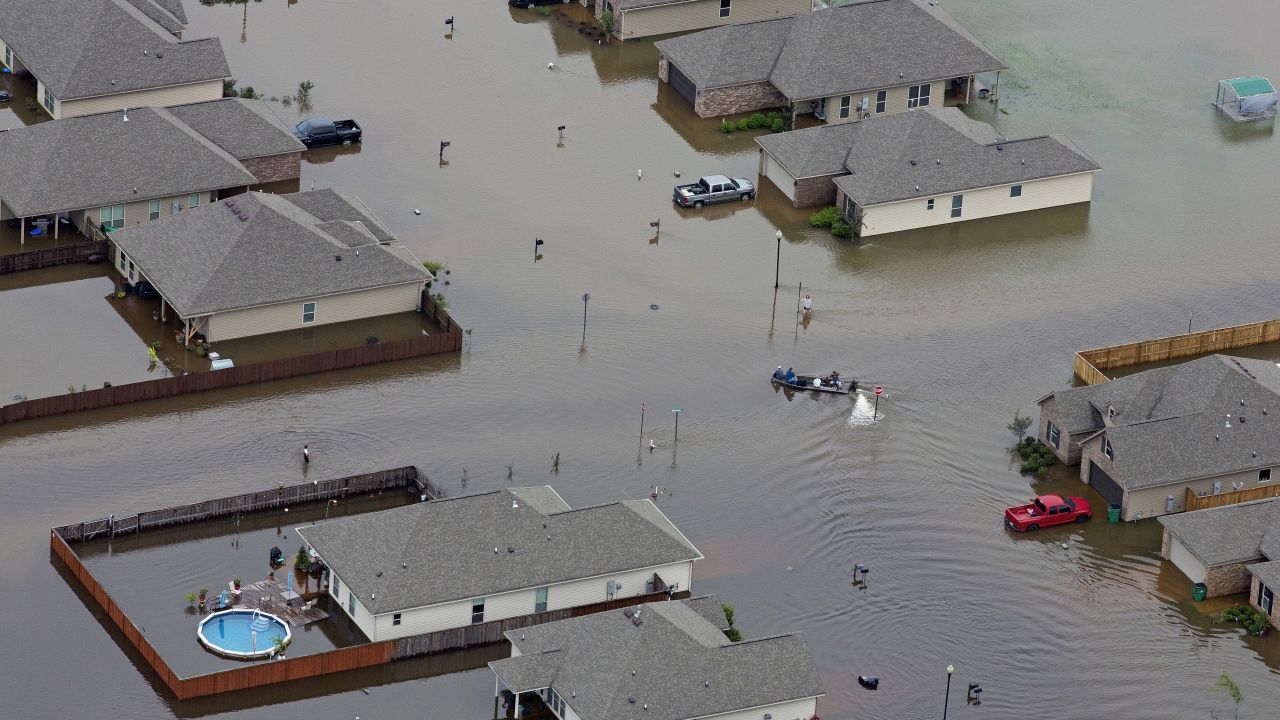 A boat motors between flooded homes after torrential rainfail in Hammond, Louisiana.