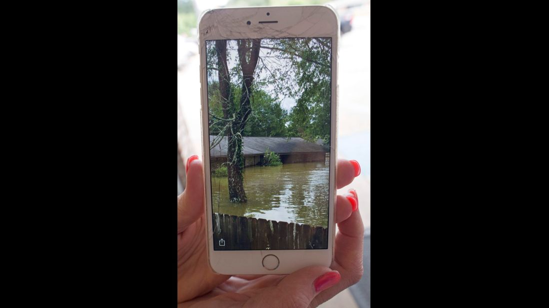 Noel Michael holds up a cell-phone photo of her flooded home in Livingston, Louisiana, on Monday, August 15.