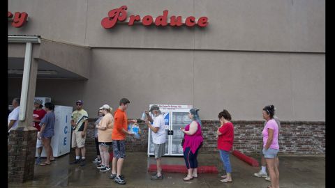 Eli Turnage hands out water to people waiting in line at Carter's Supermarket in Livingston on August 15.