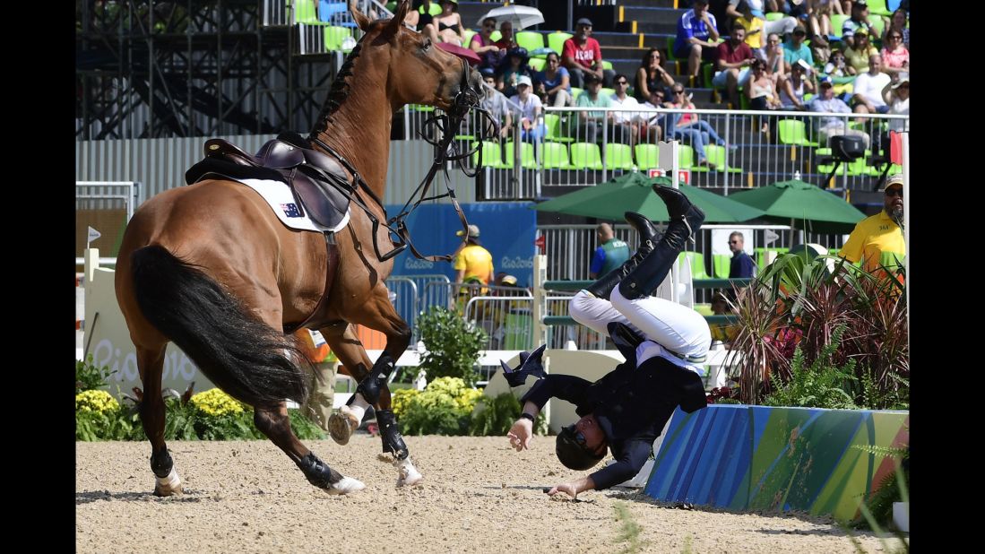 Australian equestrian Scott Keach falls off his horse, Fedor, during the individual jumping competition.
