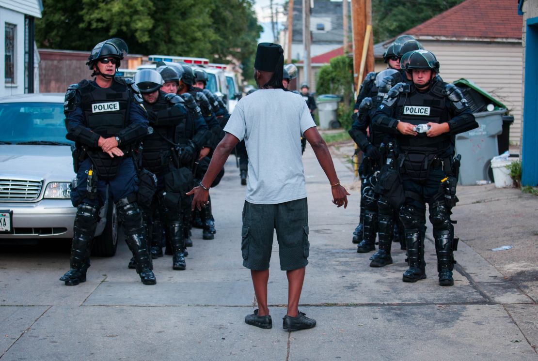 A man talks to police in riot gear in Milwaukee on Aug. 15.