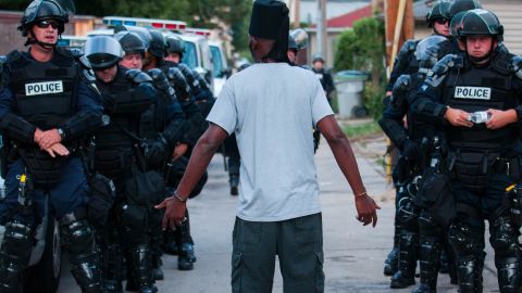 A man talks to police in riot gear in Milwaukee on Aug. 15.