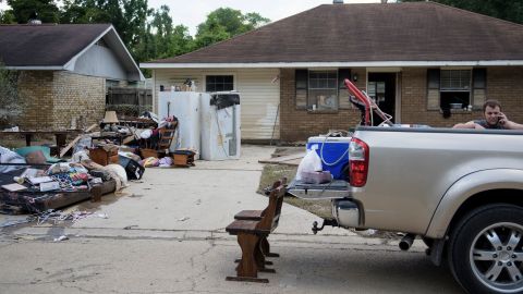 A man talks on his phone while helping salvage items from a house in Denham Springs on August 17.