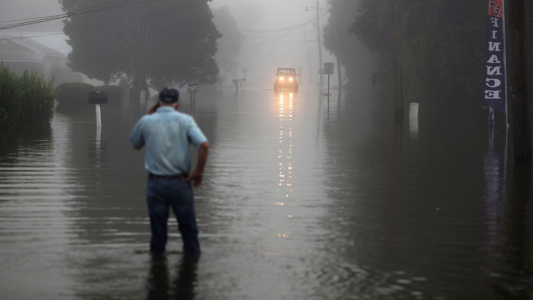 Gary Schexnayder stands in a flooded street in Sorrento as an early morning fog blankets the area August 17.