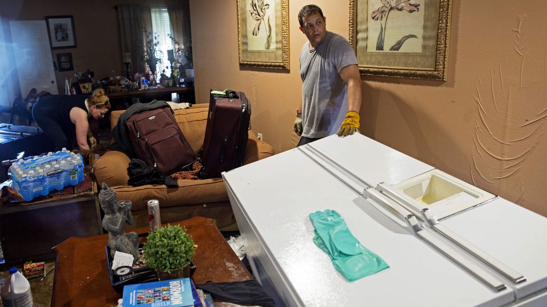 Raymond Lieteau waits for help to move a refrigerator as his friend Melissa Lockhart helps clean up the living room in his flood-damaged home in Baton Rouge on August 16. Lieteau had more than 5 feet of water in his home. 