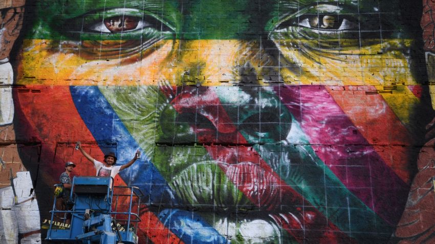 Brazilian artist Eduardo Kobra stands next to his huge mural representing the five continents, at the Olympic Boulevard, in Rio de Janeiro, Brazil, on July 14, 2016. / AFP / CHRISTOPHE SIMON        (Photo credit should read CHRISTOPHE SIMON/AFP/Getty Images)