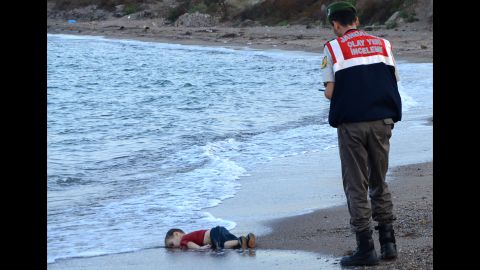 A Turkish police officer stands next to a migrant child's body off the shores of Bodrum, Turkey, on September 2, 2015 after a boat carrying refugees sank on approach to the Greek island of Kos. The picture sent shockwaves across the globe, highlighting the plight of refugees fleeing from war.