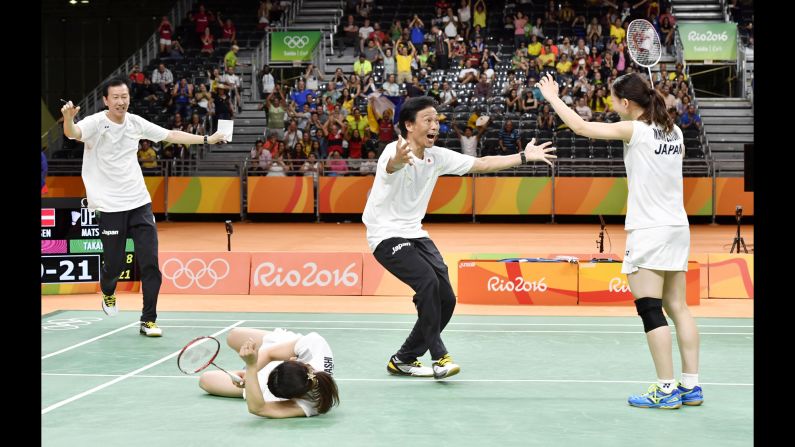 Japan's Misaki Matsutomo, right, and Ayaka Takahashi, second from left, celebrate with their coaches after winning the doubles final in badminton.