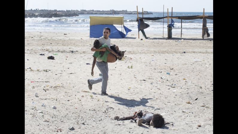 <strong>2014: Gaza City </strong>-- A man carries a child as another lies dead after an Israeli airstrike on a Gaza City beach in July 2014. At least four boys, ages 9 to 11, were killed. The Israeli military investigated the tragedy and reported that the location of the attack was known to be a compound of Hamas police and naval forces. "Tragically, in the wake of the incident it became clear that the outcome of the attack was the death of four children who had entered the military compound for reasons that remain unclear," <a href="index.php?page=&url=http%3A%2F%2Fwww.cnn.com%2F2015%2F06%2F11%2Fmiddleeast%2Fisrael-gaza-beach-bombing%2F" target="_blank">the report stated.</a>