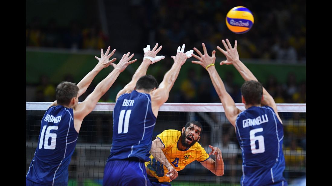 Brazilian volleyball player Wallace de Souza, in yellow, spikes the ball in the gold medal game against Italy. The Brazilians won.