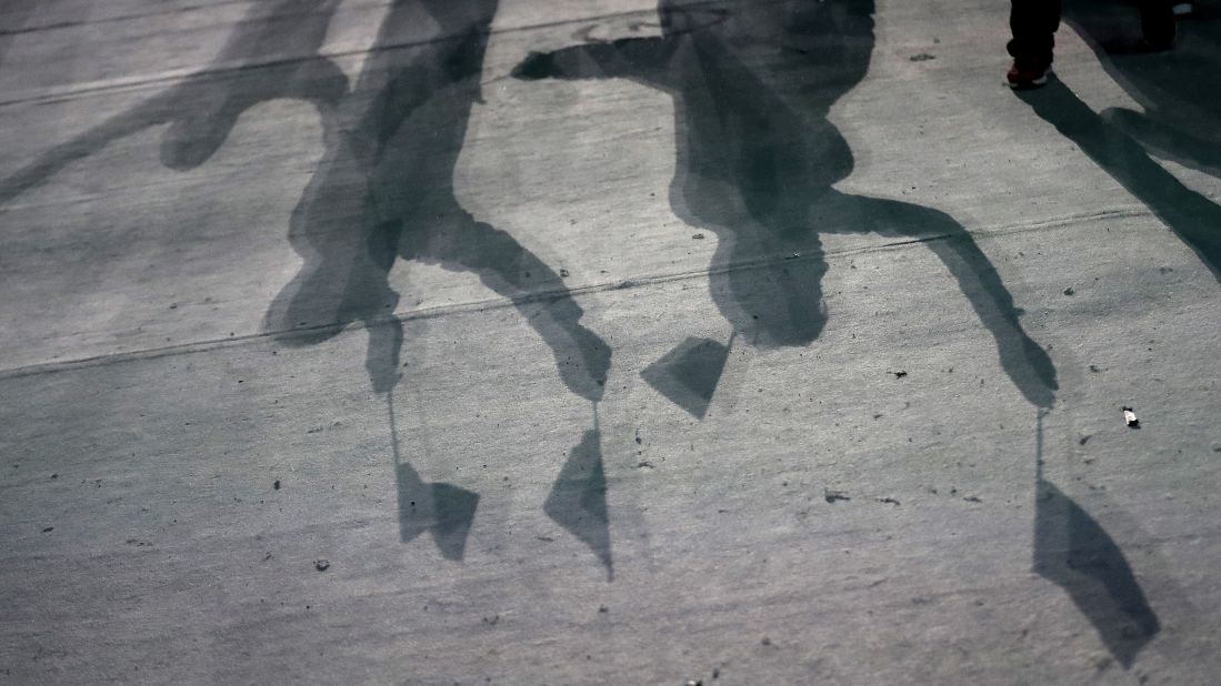 Athletes cast shadows as they wave flags.