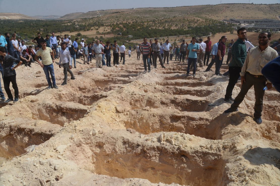 People wait Sunday near freshly dug graves for the victims of the Gaziantep blast.