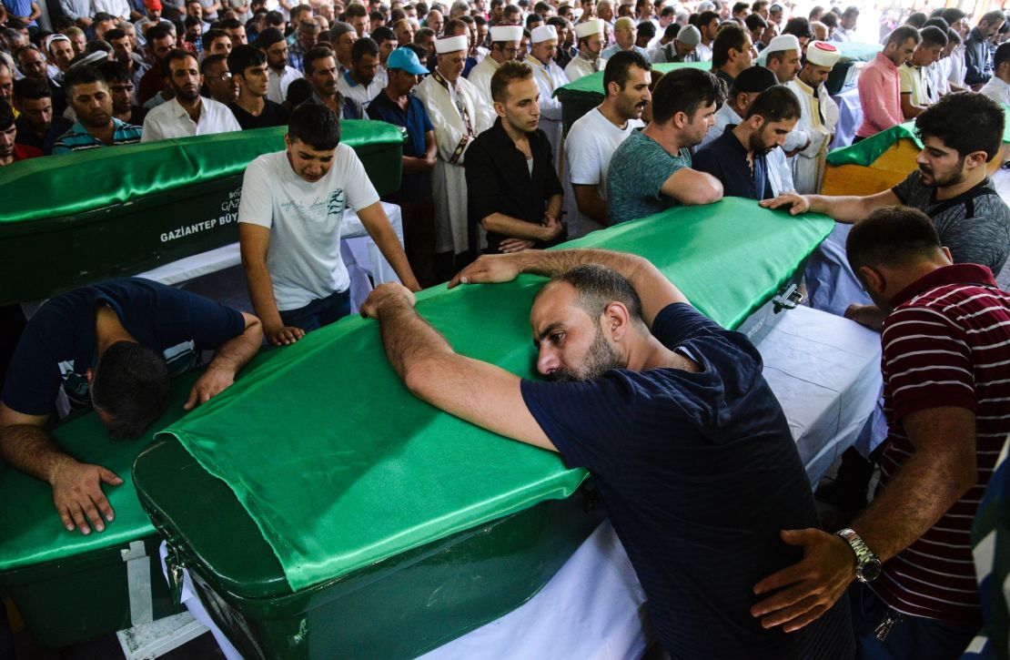 A mourner leans on a coffin at a funeral for victims of the Gaziantep blast.
