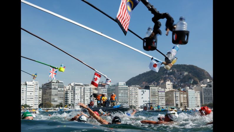 Refreshment bottles are held over women competing in the 10-kilometer open-water swim on Monday, August 15.