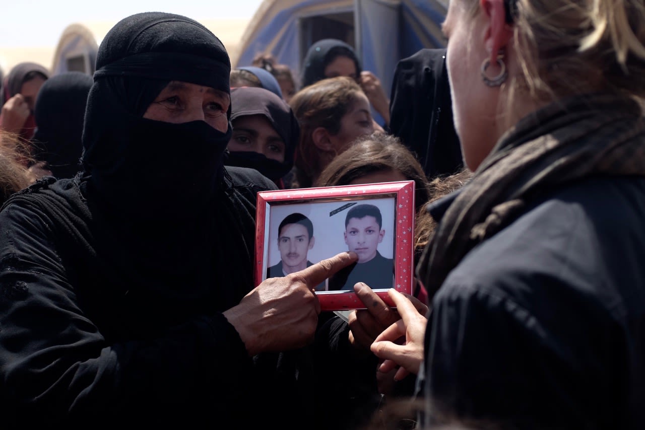 Iraqi mother Piswa Treish holds a picture of her son (right) who was killed by ISIS.