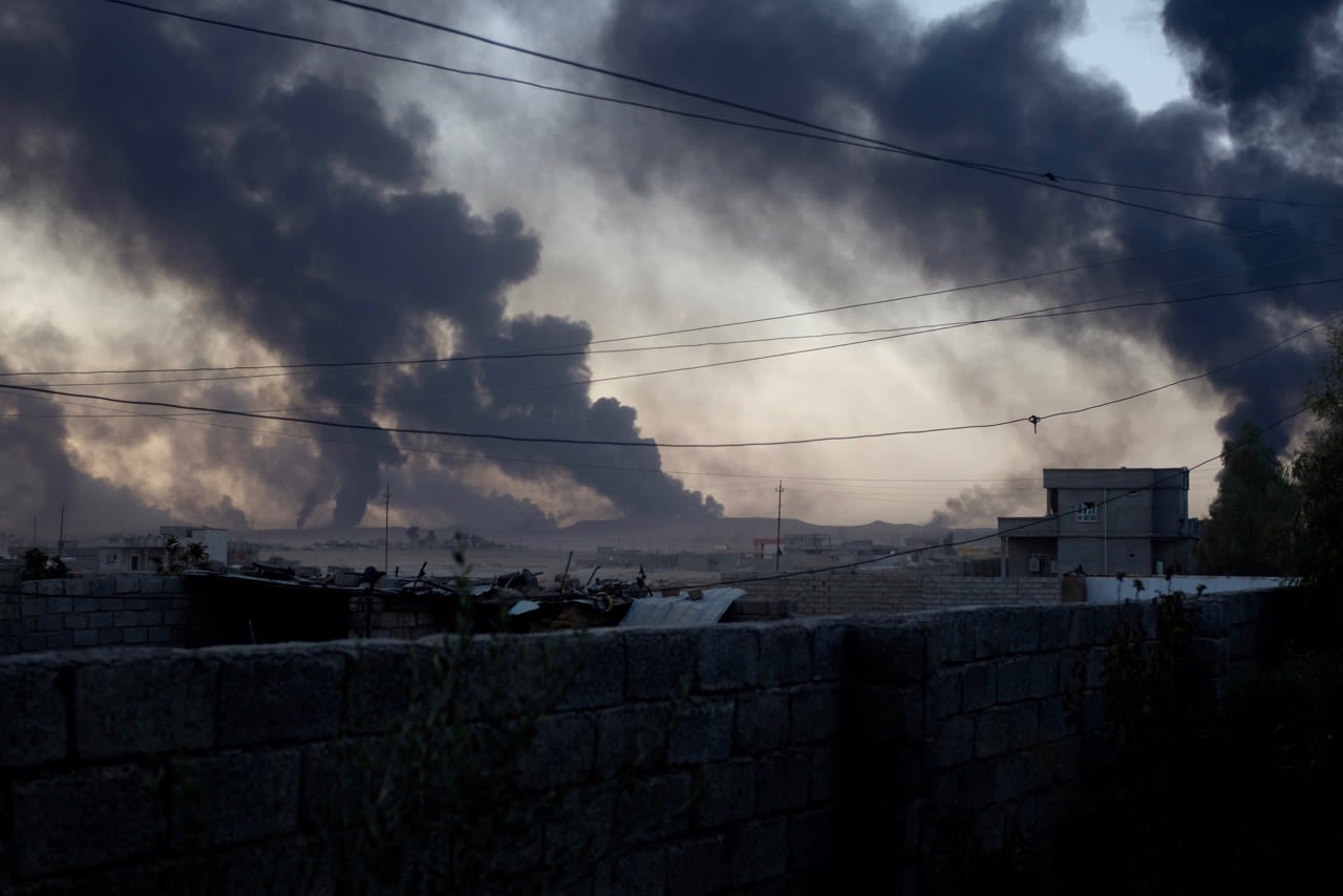 Smoke rises from al-Qayyara in the late afternoon light, as ISIS burns crude oil to block visibility from above.