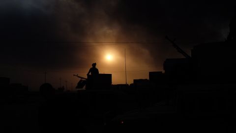 An Iraqi soldier stands guard on the outskirts of Qayyarah, under apocalyptic skies filled with smoke.