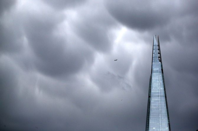 An airplane passes rain clouds above The Shard skyscraper in London, England. 