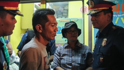Officers and the neighborhood "captain" Leny Glivano talk to a resident of Barangay Libis during a late night visit.