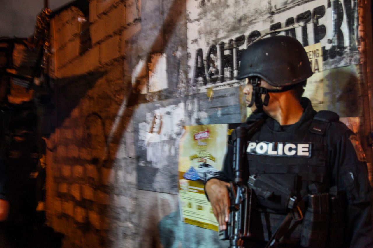 An armed officer accompanies a "knock and plead" operation in the Bangaray Labis slum in Quezon City.