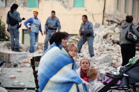 Survivors sit among the rubble of a house in Amatrice on August 24.